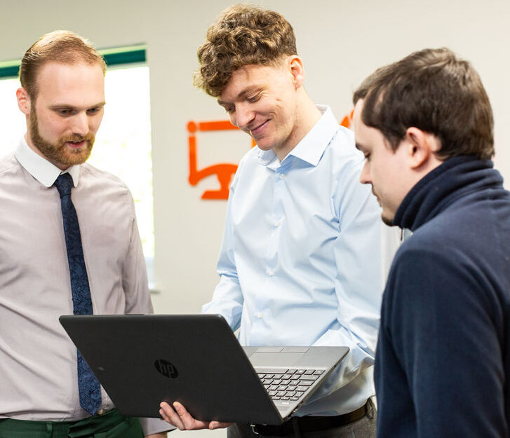 three staff members looking at a laptop