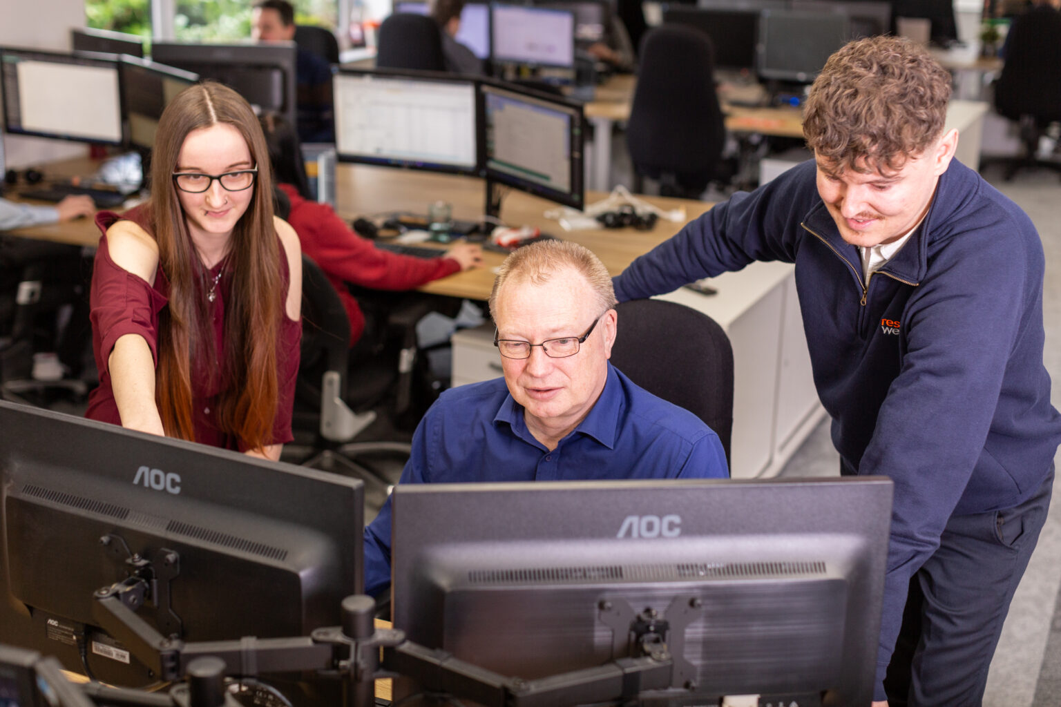 three staff members looking at a computer.
