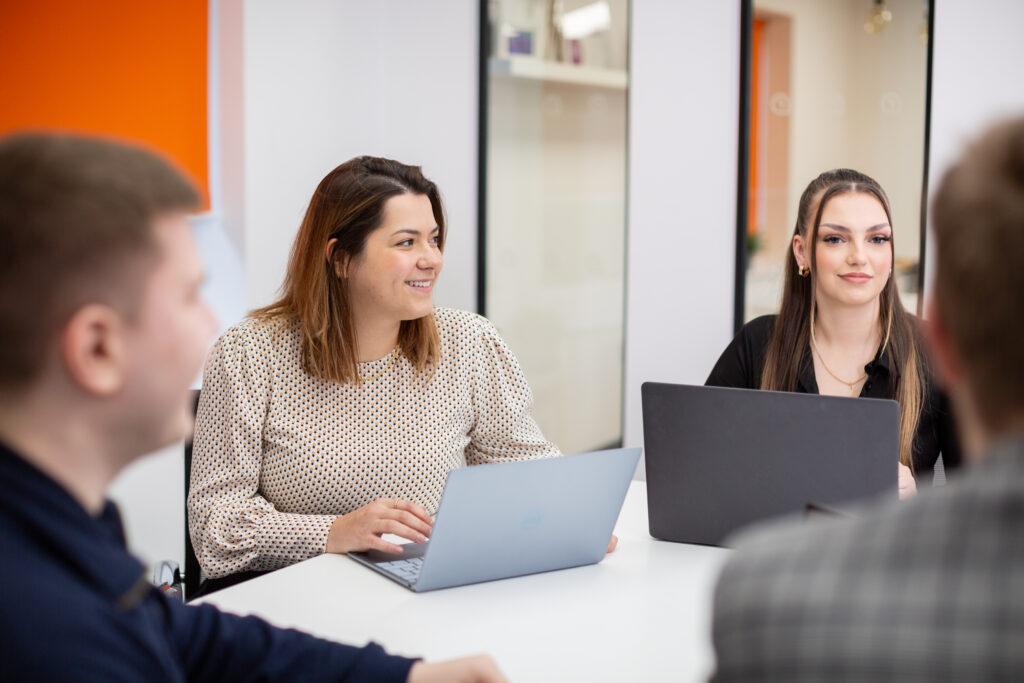 two women in front of laptops smiling