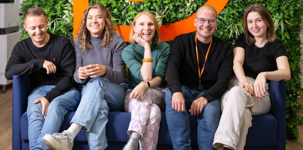 Three staff mebers sat on a safoa with the Resolve logo behind them. They are all smiling.
