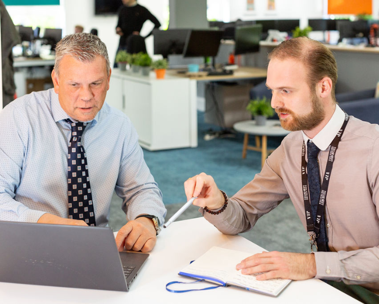 Two staff members chatting and looking at a comouter screen