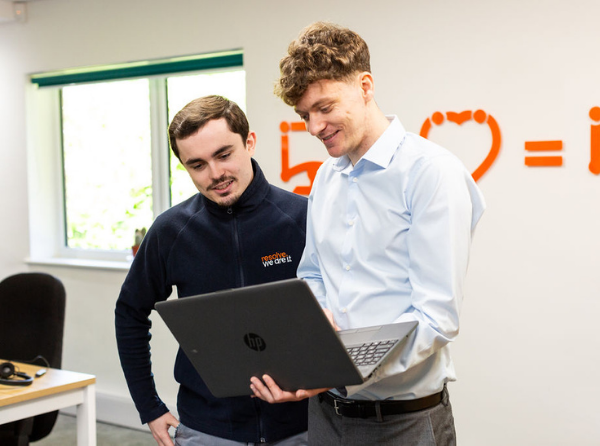 Photo of two resove members stood next to each other looking at a laptop.