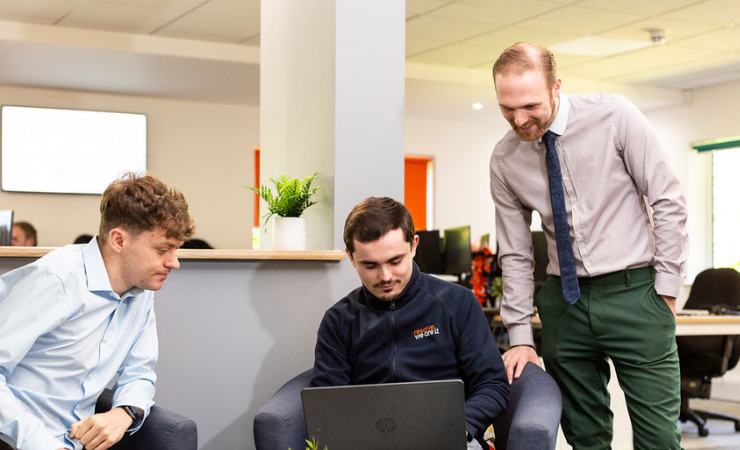 Three staff members looking at a laptop