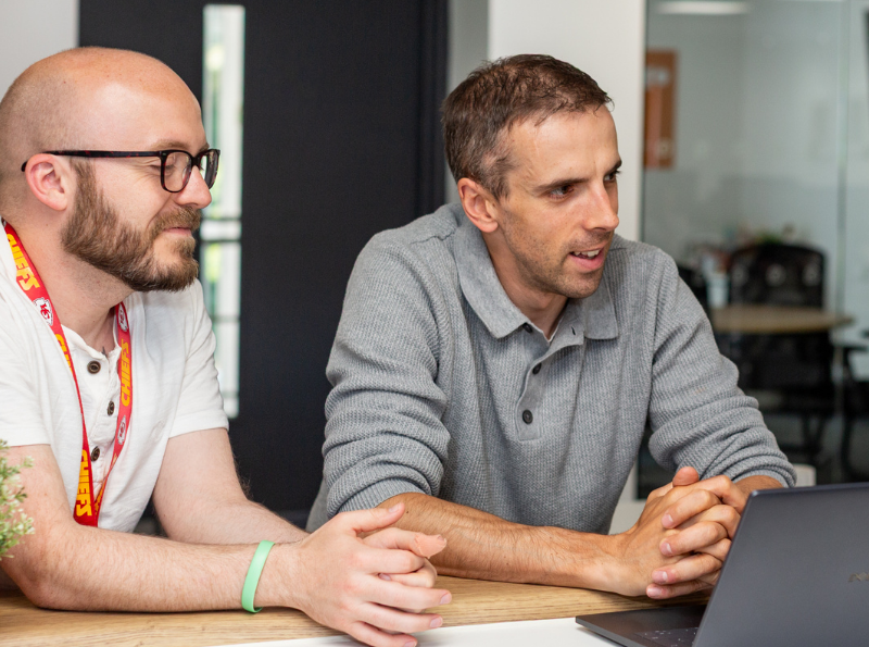 Photo of two staff members looking at a laptop together