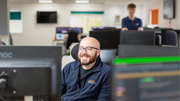 Photo of very happy staff member behind his computer.