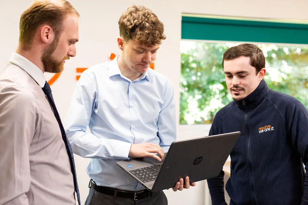 Three people around a laptop.