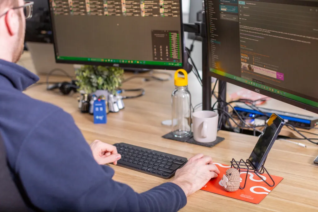 Hands on keyboard and mouse in front of computers