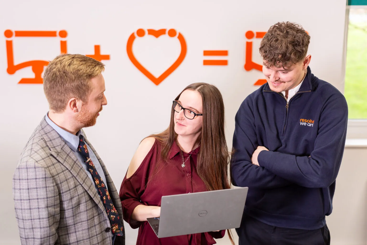 three people talking and holding a laptop